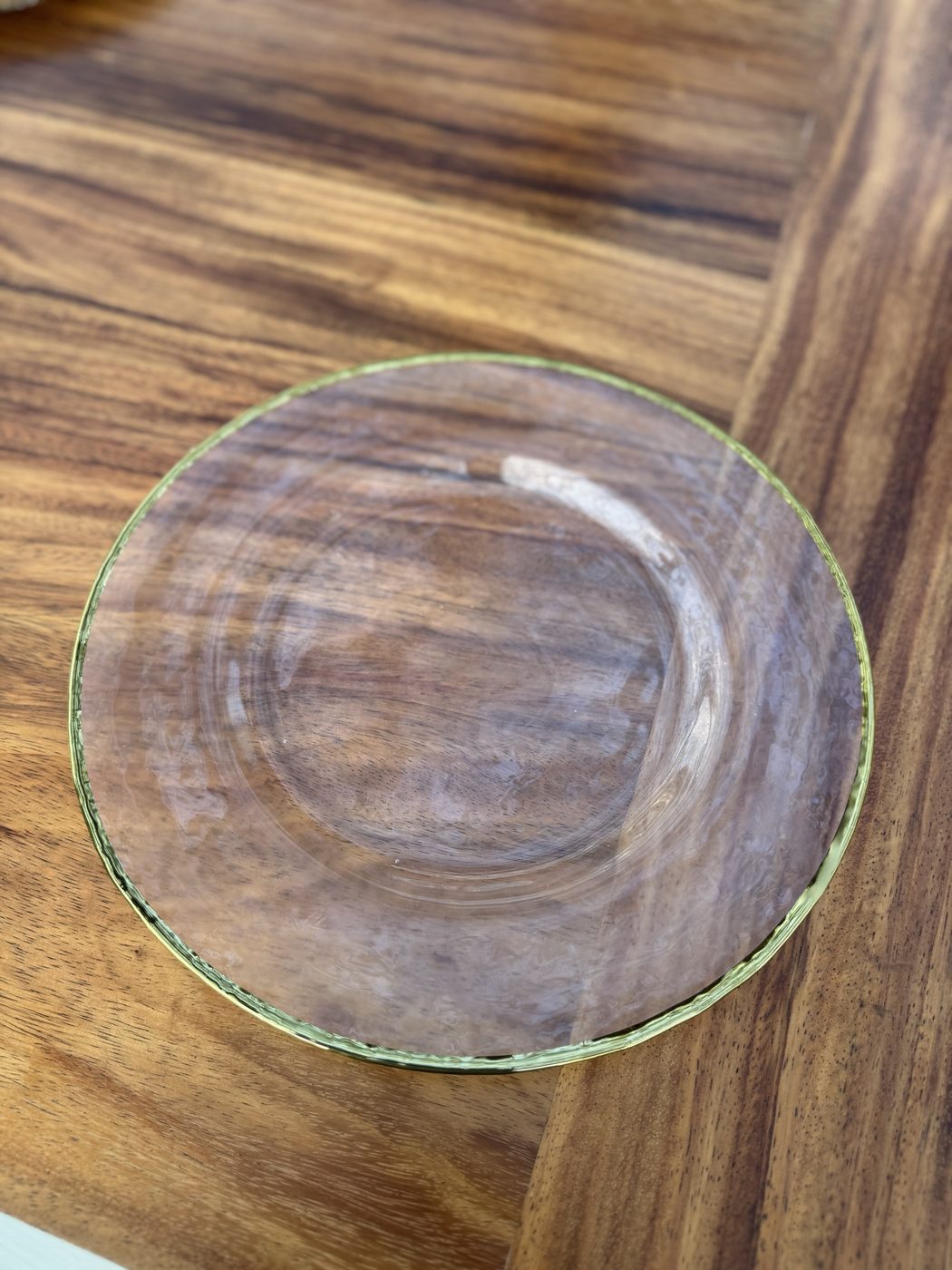Golden glass charger: Clear glass charger with a golden rim on a wood table